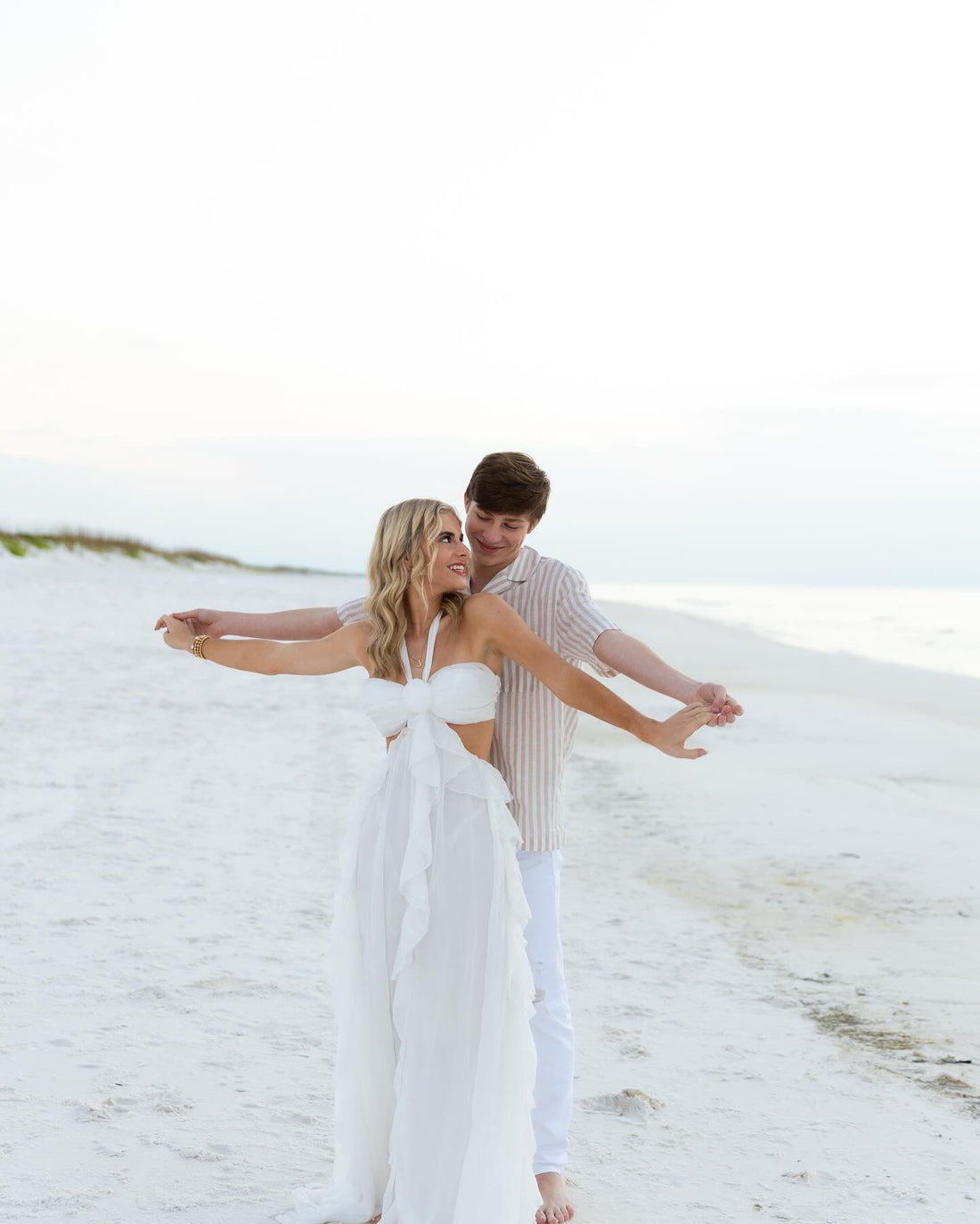 Girl wearing wedding dress on beach with her husband